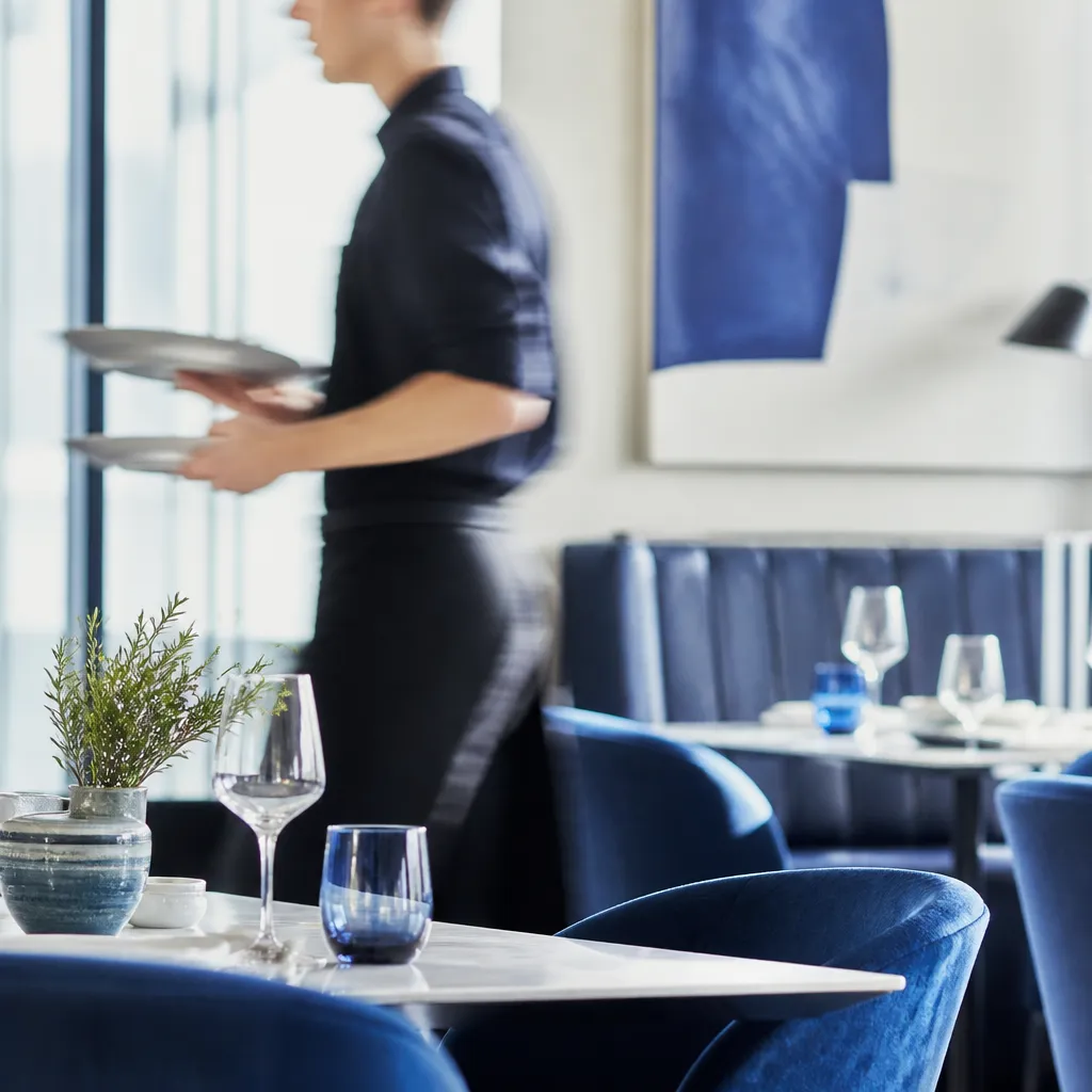 Jeune serveur portant des assiettes dans un restaurant, job étudiant type